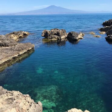 Acqua cristallina e color smeraldo, vista Etna della Baia del Silenzio